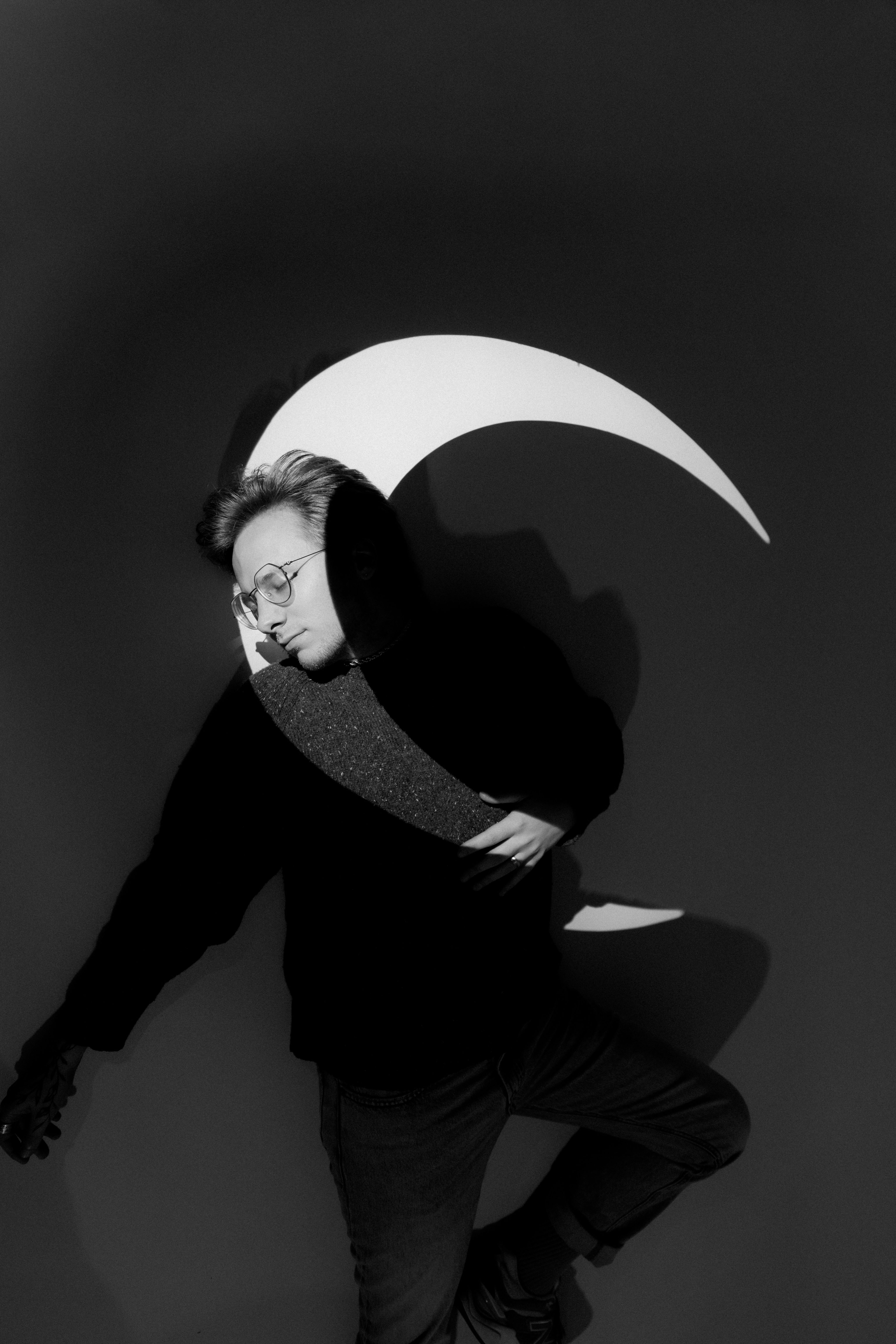 Man with glasses holding a crescent moon shape
