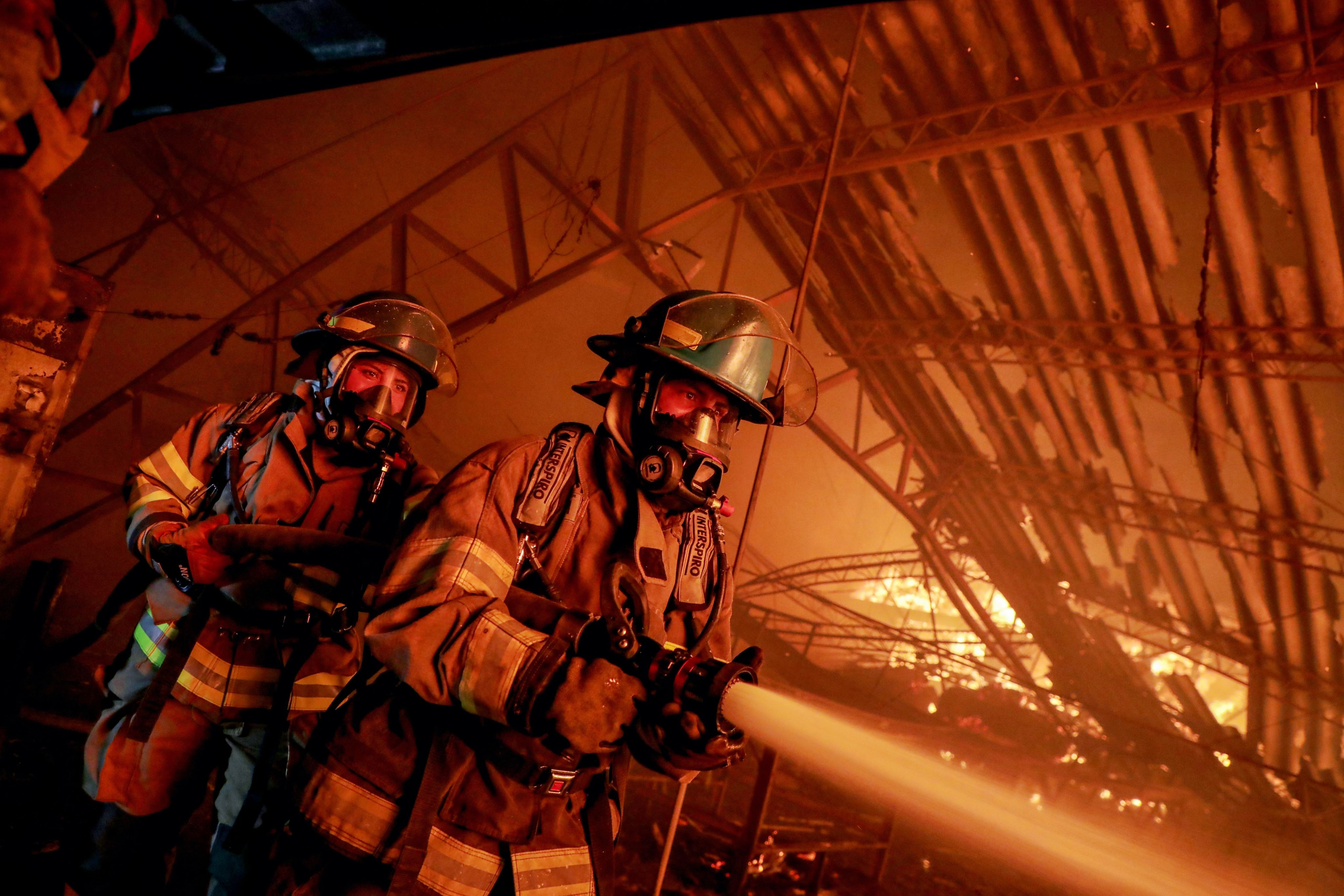 Firefighters combat a blaze with a water hose.