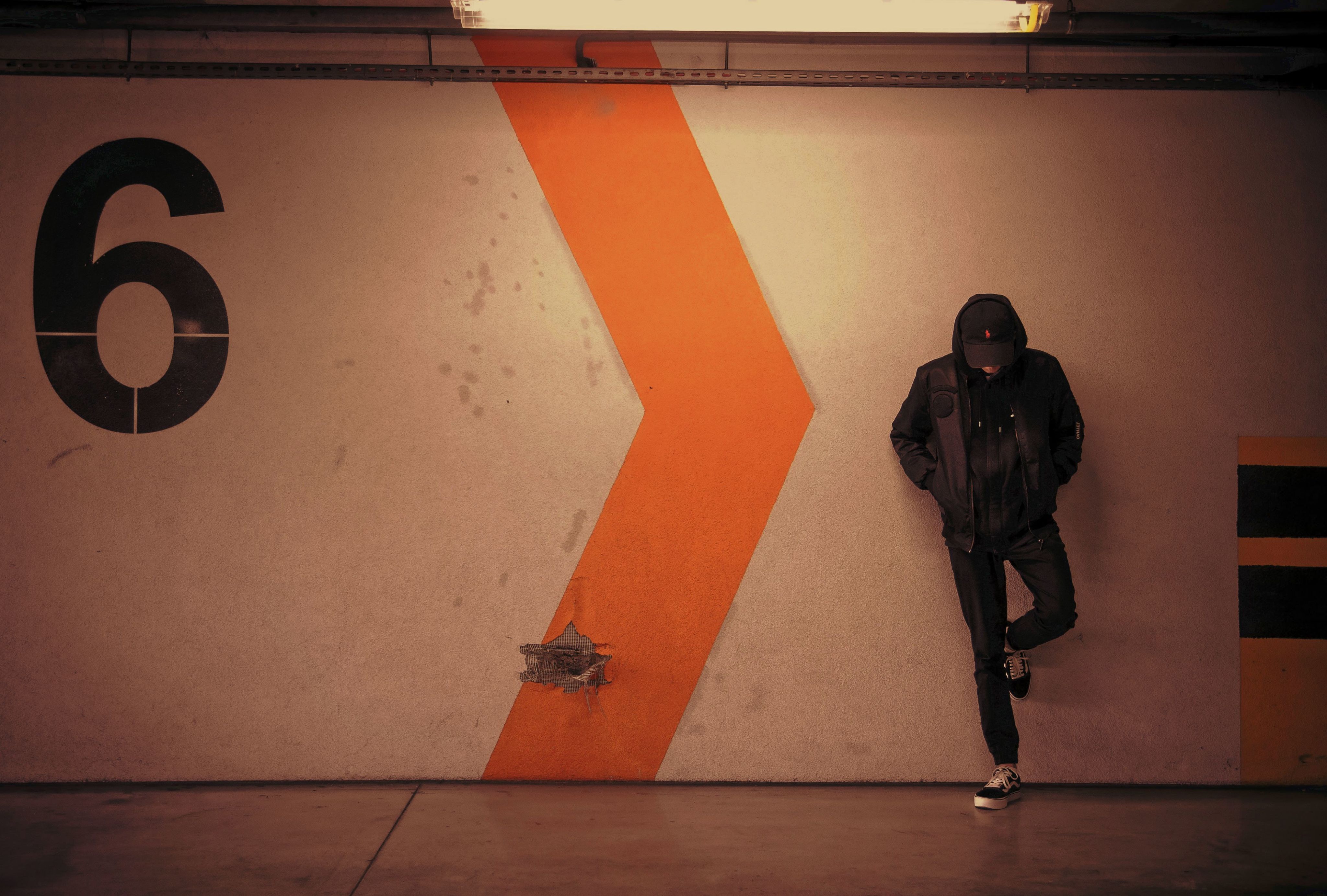 man leaning on white wall of the parking area